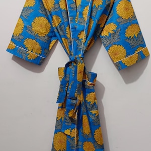 May include: A blue robe with a yellow floral pattern and white trim. The robe is tied at the waist with a matching belt. The text "UMARIA FASHION" is visible on a tag.