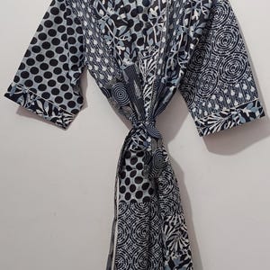 May include: A patterned robe with a tie closure. The robe features a mix of black, white, and light blue patterns, including polka dots, floral designs, and geometric shapes. The label reads "UMARIA FASHION".