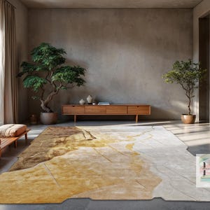 Peut inclure: Un grand tapis de sol abstrait de forme irrégulière. Il présente un mélange de couleurs or, marron et crème, créant un effet texturé et superposé. Le tapis est dans un salon moderne avec des meubles en bois et des plantes en pot.