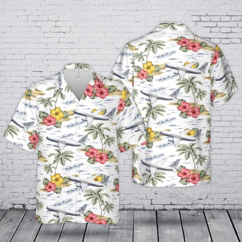 May include: A short-sleeve button-down shirt featuring a white background with an all-over print of airplanes, green palm trees, and red and yellow hibiscus flowers. The shirt has a classic collar and a front button closure with a straight hem.