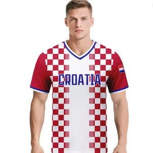 May include: A Croatia football shirt in white and red check pattern, with the word "CROATIA" in blue across the chest. The shirt features a V-neck and a small Croatian flag on the sleeve.