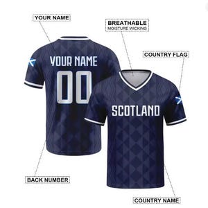 May include: A dark blue V-neck jersey with a geometric diamond pattern, white trim on the sleeves and collar, and the text SCOTLAND on the front. The back features the text YOUR NAME and the number 00, with a small Scottish flag on the sleeve.