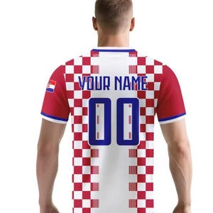 May include: A red, white, and blue football shirt with the Croatian flag on the left sleeve. The back of the shirt features the text "YOUR NAME" above the number "00" in blue. The shirt has a checkered pattern.