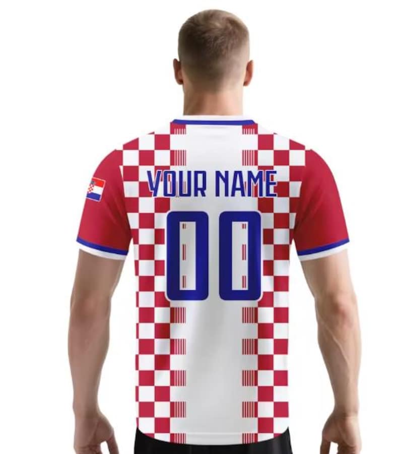 May include: A red, white, and blue football shirt with the Croatian flag on the left sleeve. The back of the shirt features the text "YOUR NAME" above the number "00" in blue. The shirt has a checkered pattern.