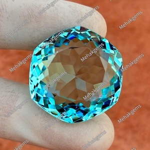 Può includere: Una grande gemma sfaccettata con una sorprendente tonalità blu. La gemma è tenuta da una mano guantata, che mostra il suo taglio e la sua chiarezza intricati. Le sfaccettature della gemma riflettono la luce, creando un'esposizione brillante. Lo sfondo è di un caldo colore arancione-marrone.