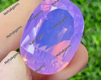 May include: An oval-shaped, faceted lavender gemstone with a smooth, polished surface. The stone displays a translucent, light purple hue with subtle internal reflections. The text Mehakgems is repeated across the image surface.