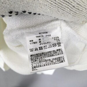 May include: A white fabric garment label featuring black text including KC3008, TMK(3) 2102, and material composition details of 95% cotton and 5% polyurethane. The label displays various laundry care symbols and Japanese text instructions for garment maintenance.