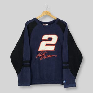 May include: Navy blue sweatshirt with black sleeves. The number "2" is displayed in white with an orange outline, above the name "Rusty Wallace" in red script. The sweatshirt is hanging on a wooden hanger.