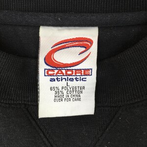 May include: Close-up of a black sweatshirt tag. The tag features the "CADRE athletic" logo in red and white. The tag also includes the fabric composition: 65% polyester, 35% cotton. The tag also states "MADE IN CHINA".