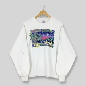 May include: White sweatshirt with a colorful graphic of a tropical scene. The design features palm trees, a sunset, and a crescent moon. The sweatshirt is hanging on a wooden hanger.
