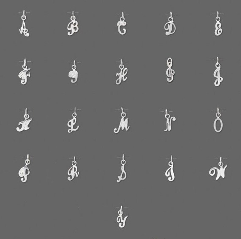 Op de afbeelding: Een set van 26 zilveren bedels, elk met een andere letter van het alfabet in een cursief schrift.