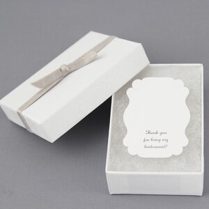 May include: White gift box with a gray ribbon and a white card inside. The card has the text "Thank you for being my bridesmaid!"