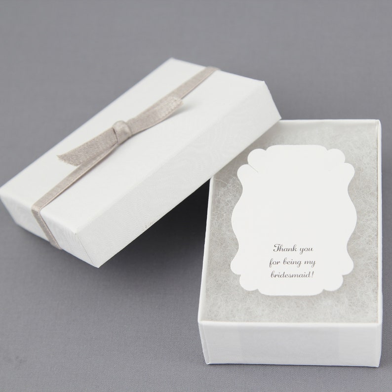 May include: White gift box with a gray ribbon and a white card inside. The card has the text "Thank you for being my bridesmaid!"