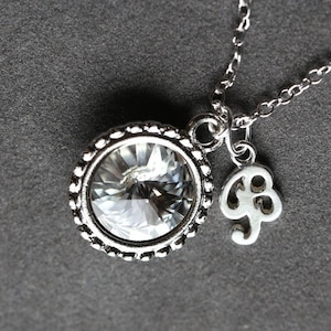 Puede incluir: Un collar de plata con un gran colgante de cristal transparente y un pequeño dije en forma de nota musical.