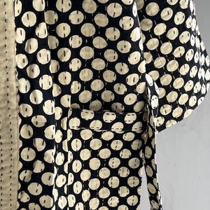 Peut inclure: Une robe de style kimono noire et cr&egrave;me avec un motif r&eacute;p&eacute;titif de grands cercles blanc cass&eacute;. La robe a une poche et une ceinture assortie. Le tissu est cousu avec un motif pointill&eacute;.