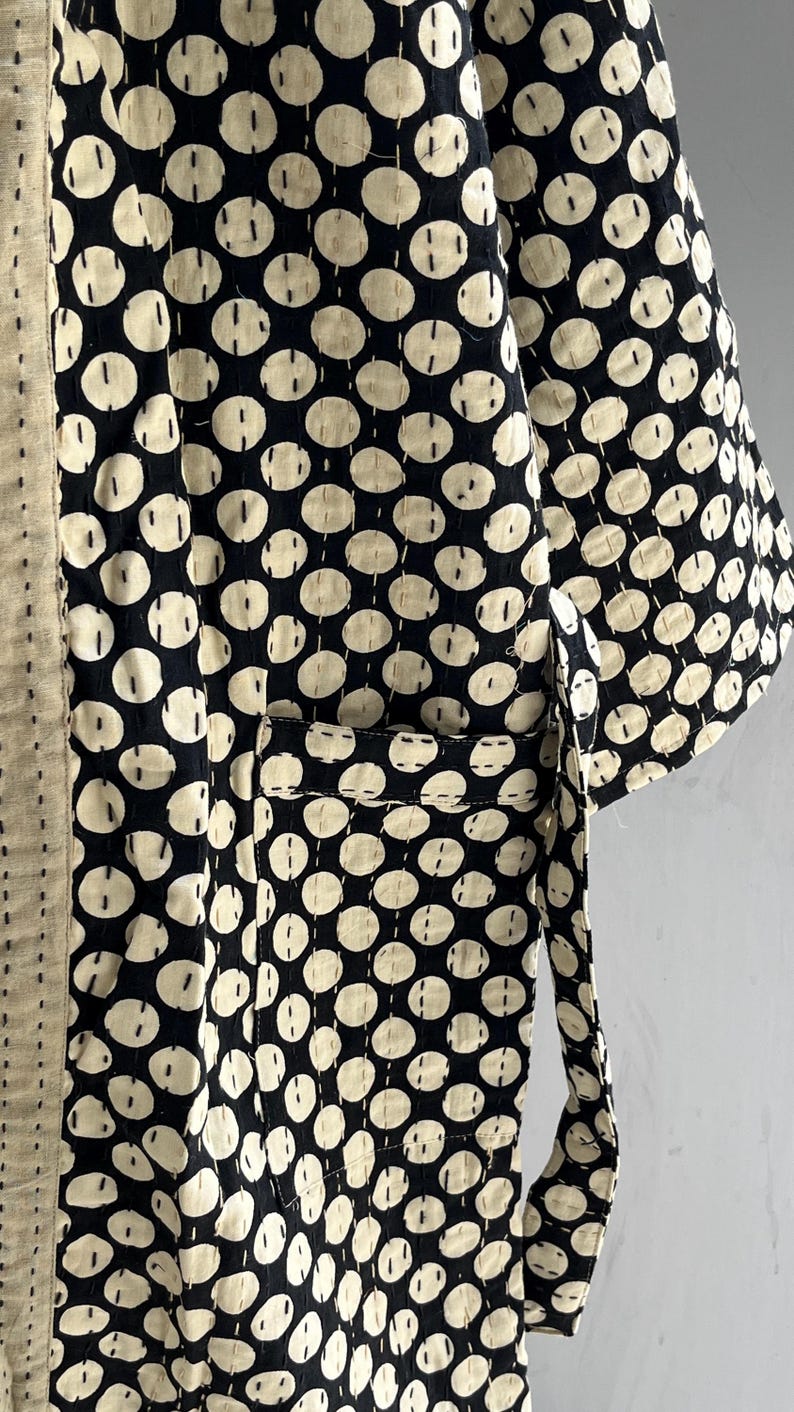 Peut inclure: Une robe de style kimono noire et cr&egrave;me avec un motif r&eacute;p&eacute;titif de grands cercles blanc cass&eacute;. La robe a une poche et une ceinture assortie. Le tissu est cousu avec un motif pointill&eacute;.