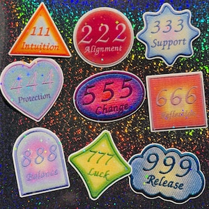 May include: A set of nine embroidered patches featuring various shapes and colors, each displaying a three-digit number and a corresponding word: 111 Intuition, 222 Alignment, 333 Support, 444 Protection, 555 Change, 666 Reflection, 888 Balance, 777 Luck, and 999 Release.