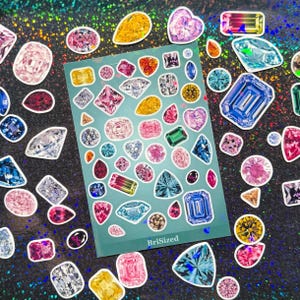 May include: A teal sticker sheet featuring a variety of colorful gemstone illustrations in diverse shapes and cuts, including round, oval, pear, and emerald, with the text BriSized printed in white at the bottom center of the sheet.