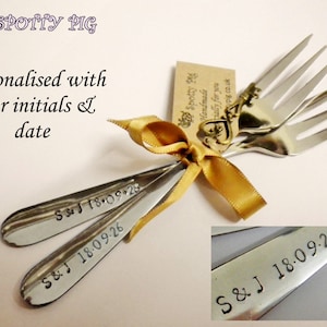 May include: Two silver forks tied together with a gold ribbon and a small tag that says "Spotty Pig Handmade" and "Spotty Pig.co.uk". The forks are engraved with "S&J 18.09.26".