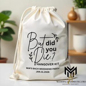 Peut inclure: Sac en coton blanc cassé avec cordon de serrage, portant l'inscription "But did you Die?" et "Hangover Kit". En dessous, on peut lire "Mia's Bach Weeknd Party Jan.31.2026". Le sac porte un logo "Wedding Favors Decors".