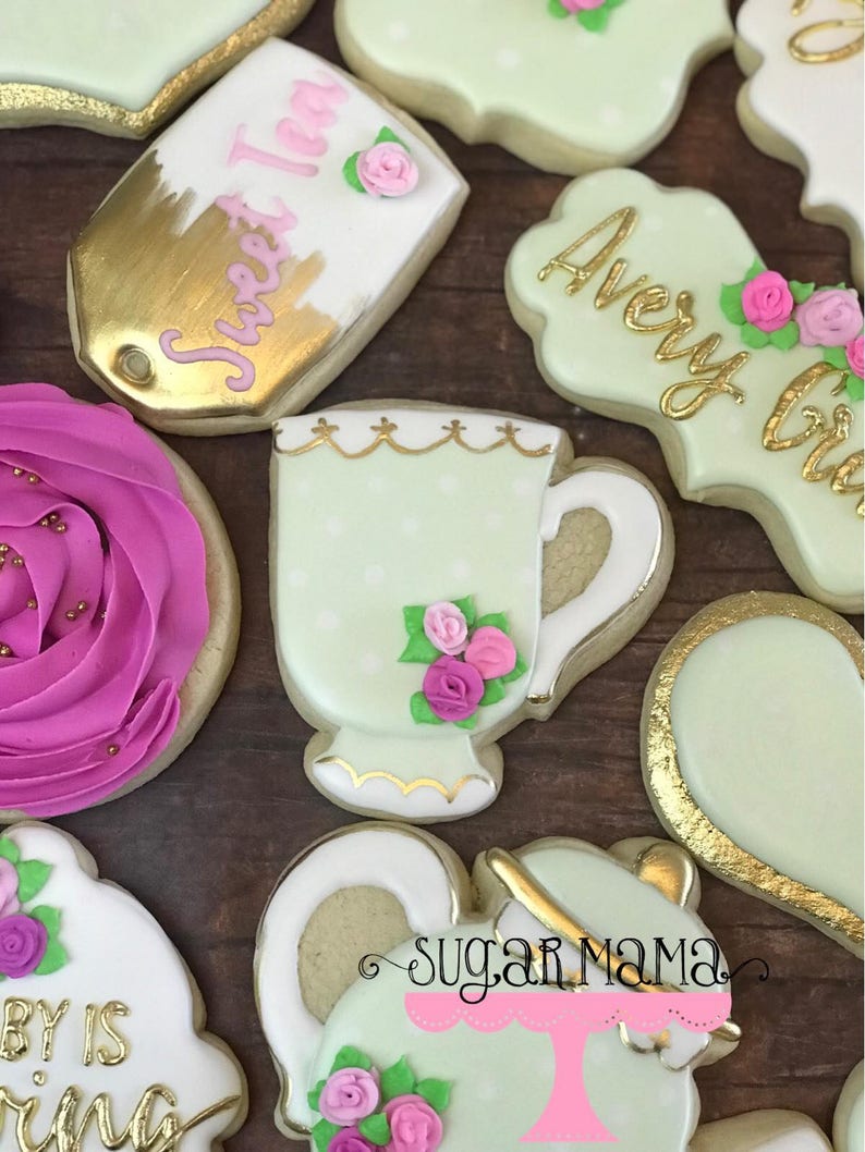 May include: A set of decorated sugar cookies with a tea party theme. The cookies are decorated with green, pink, and gold icing. The cookies feature a teacup, teapot, and a tag that says "Sweet Tea".