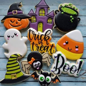 May include: A set of ten Halloween-themed sugar cookies decorated with colorful icing. The cookies feature a ghost, a spider, a bat, a witch's hat, a pumpkin, a candy corn, a cauldron, a haunted house, and the words "trick or treat" and "boo!"