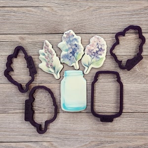 Peut inclure: Cinq emportes-pièces, dont deux motifs de fleurs de lilas, deux motifs de bocaux en verre et un motif de feuille. Les emportes-pièces sont en métal et de couleur gris foncé.