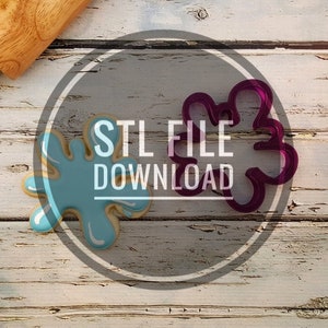 May include: Two cookie cutters on a wooden surface. One is a blue splatter design and the other is a purple flower design. The text "STL FILE DOWNLOAD" is in the center of the image.