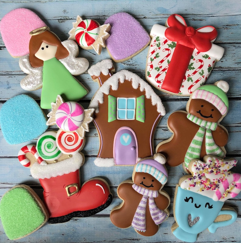 Puede incluir: Surtido de galletas de az&uacute;car con tem&aacute;tica navide&ntilde;a decoradas con glaseado y chispas. Las galletas incluyen una casa de jengibre, un mu&ntilde;eco de nieve, una media, un bast&oacute;n de caramelo, un regalo, una estrella y un &aacute;ngel.