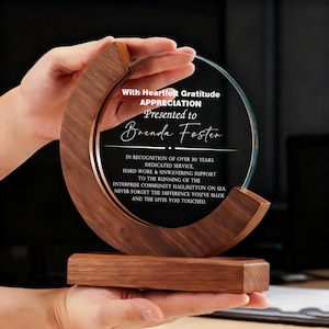 May include: A clear glass award with a circular design, set in a wooden frame. The award is engraved with text that reads "With Heartfelt Gratitude, Appreciation, Presented to Brenda Foster."