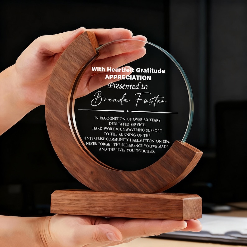 May include: A clear glass award with a circular design, set in a wooden frame. The award is engraved with text that reads "With Heartfelt Gratitude, Appreciation, Presented to Brenda Foster."