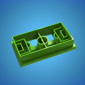 Könnte beinhalten: Ein hellgrüner Ausstecher aus Kunststoff in Form eines Fußballfeldes. Der Ausstecher hat die Markierungen des Spielfelds, einschließlich der Torräume, des Mittelkreises und der Mittellinie. Der Hintergrund ist ein Blauton.