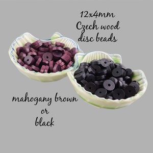 May include: Two small bowls filled with 12x4mm Czech wood disc beads. One bowl contains mahogany brown beads, the other contains black beads.