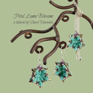 May include: A turquoise blue beaded necklace and earrings set in the shape of a flower. The necklace and earrings are hanging on a brown metal display stand. The set is called "Petal Luma Blossom" and is a tutorial by Sharri Moroshok.