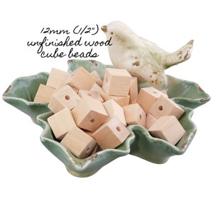 Puede incluir: Un bol lleno de cuentas de madera cúbicas sin terminar de 12 mm (1/2"). Las cuentas tienen un agujero perforado en el centro de cada cubo.