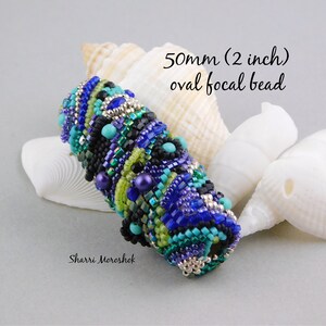 May include: A 2 inch oval focal bead made of blue, green, turquoise, and black beads. The bead is surrounded by seashells.