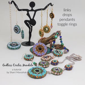 May include: Beaded jewellery collection featuring earrings, necklaces, and pendants in turquoise, blue, and gold. The items are displayed on a black metal stand and a bronze hand. Text on the image reads "Endless Circles Mandala" and "links drops pendants toggle rings."