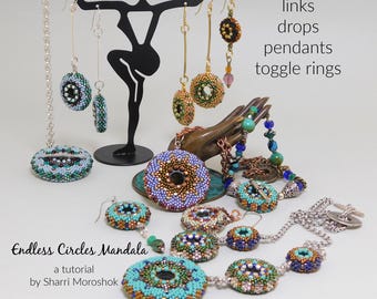 May include: A collection of beaded jewelry, including earrings, necklaces, and pendants, in various colors like turquoise, blue, and gold. The jewelry is displayed on a black metal stand and a bronze hand. Text on the image reads "Endless Circles Mandala" and "links drops pendants toggle rings."