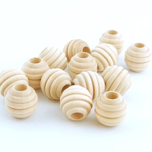 May include: A group of 15 natural wood beads with a grooved texture. The beads are round and have a hole in the center.
