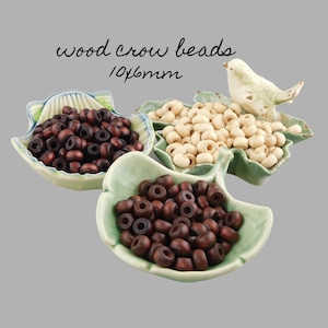 May include: Three bowls of wooden beads in brown, dark brown, and natural colors. The beads are 10x6mm in size. The bowls are shaped like leaves and are on a gray background.