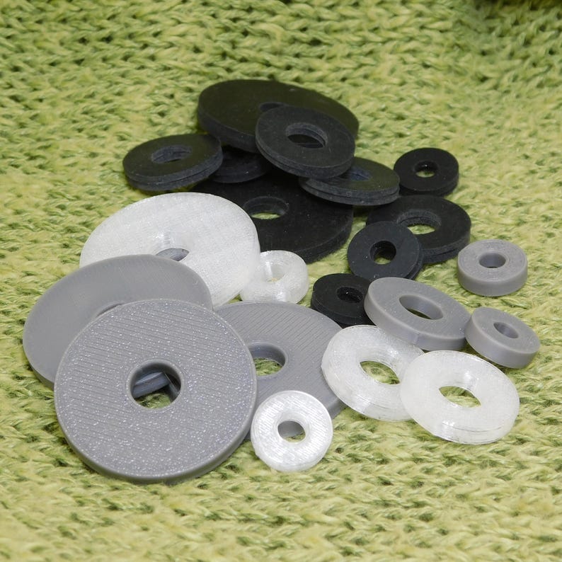 Grouping of black neoprene rubber and 3D printed washers in 3 sizes shown in pile.