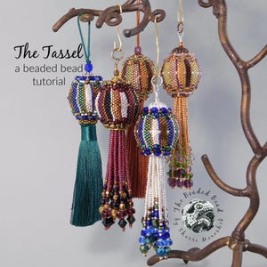May include: Five beaded ornaments with tassels hanging from a branch. The ornaments are made with colourful beads and have a geometric pattern. The tassels are made with different colours of thread. The text "The Tassel a beaded bead tutorial" is visible at the top of the image.