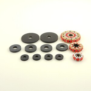 A set of black felt circles of varying sizes, along with two beaded round ornaments with red, white, and gold accents.