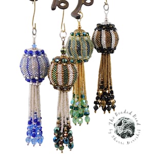 May include: Four beaded ornaments with tassels. The ornaments are striped with gold, silver, black, and blue beads. The tassels are made of beads in various colors, including gold, silver, black, blue, and green.