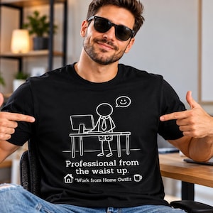 Könnte beinhalten: Ein schwarzes Kurzarm-T-Shirt mit einer weißen Strichzeichnung einer Strichmännchen-Figur an einem Schreibtisch mit Computer. Der Text lautet: Professional from the waist up. Work from Home Outfit, ergänzt durch ein Haus- und ein Tassensymbol.