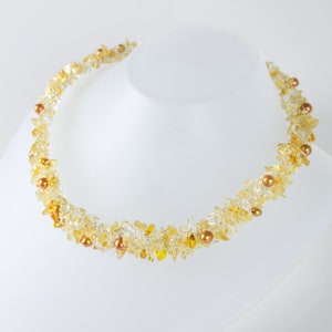 K&ouml;nnte beinhalten: Eine goldene und klare Kristallkette mit kleinen goldenen Perlen. Die Kette besteht aus kleinen, unregelm&auml;&szlig;igen Kristallst&uuml;cken und ist auf einem Draht aufgef&auml;delt.
