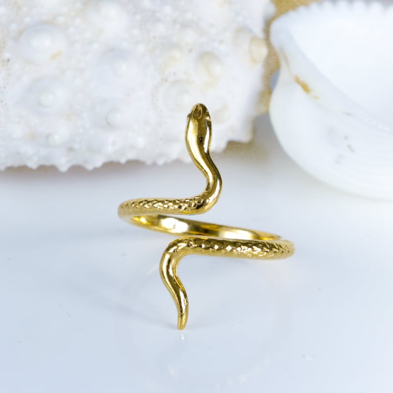 May include: A gold-toned snake ring with a textured finish. The snake is coiled and the head is raised.