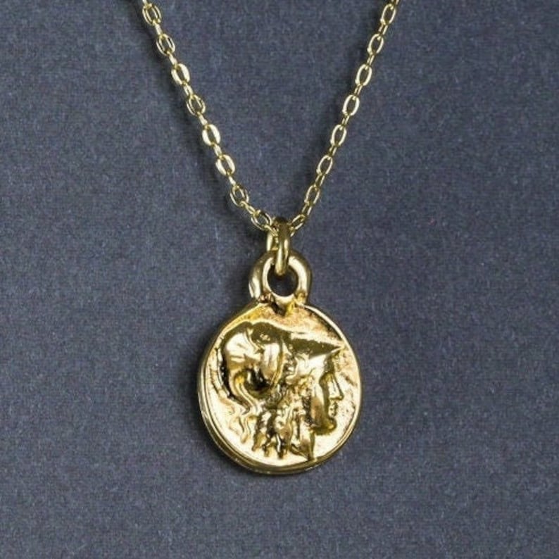Peut inclure: Un collier en cha&icirc;ne dor&eacute;e avec un pendentif rond repr&eacute;sentant un profil d&eacute;taill&eacute; d'un visage de femme avec un oiseau sur la t&ecirc;te.