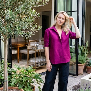 May include: A vibrant magenta button-down shirt with a collar and long sleeves, paired with loose-fitting black trousers. The shirt features a visible button placket down the center, while the trousers have a wide-leg silhouette and a solid dark finish.