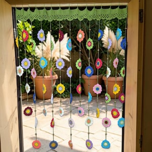 May include: A decorative door curtain featuring a light green crocheted valance with a scalloped edge. Multiple vertical strands hang from the valance, each adorned with small, multi-colored crocheted flower motifs and wooden beads.